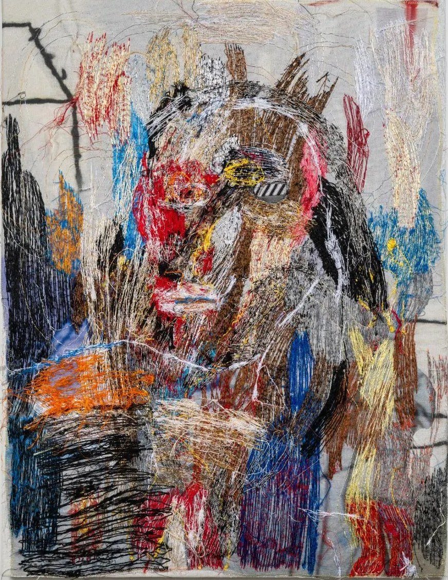 Densely stitched thread portrait in red, blue, black and cream on a white wall